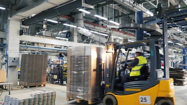 Trabalhador distribuindo mercadorias em um armazém com carregador de empilhadeira. Clipe. Homem dirigindo uma máquina de carga durante a operação da planta — Fotografia de Stock