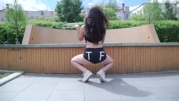 Bella ragazza vestita in pantaloncini agitare vigorosamente il bottino. Clip. Donna che balla twerk per strada — Video Stock