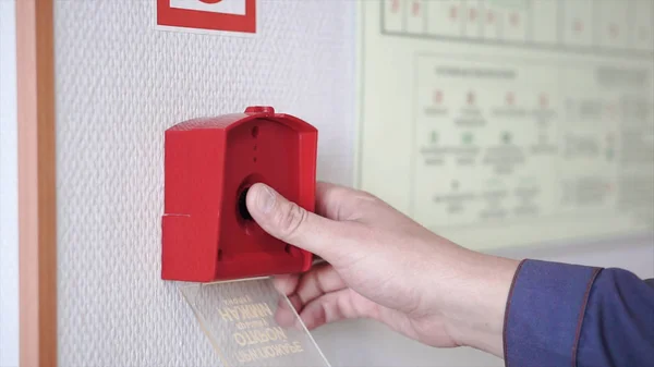 The hand of man is pushing fire alarm on the wall. Clip. Hand of man pushing fire alarm switch on the white wall as background for emergency case at the new factory building — Stock Photo, Image