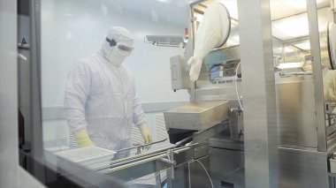 Önlük, şapka, eldiven kontrol sürecinde, fabrika üretim hattında tablet ile işçi. Kalite kontrol işçi inceleyerek hap Lab. ilaç laboratuar teknisyenleri kalitesini inceleme