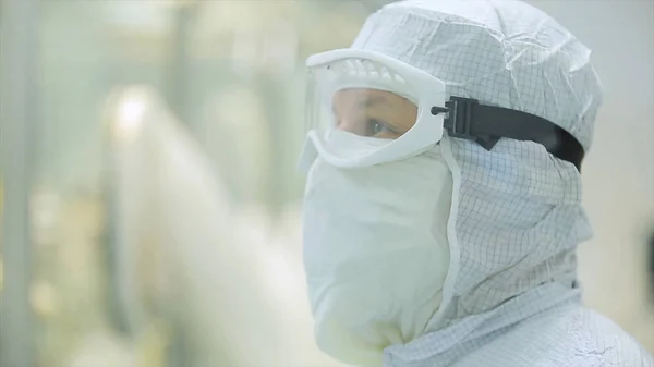 Lavoratore in grembiule, berretto, guanti con processo di controllo tablet presso la linea di produzione in fabbrica. Lavoratori di controllo di qualità esaminando pillole in laboratorio. Tecnici di laboratorio farmaceutici che ispezionano la qualità di — Foto Stock