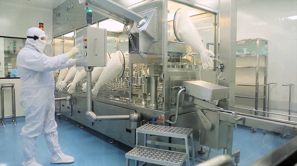 Worker in apron, cap, gloves with tablet checking process at production line in factory. Quality Control Workers Examining Pills in Lab. Pharmaceutical lab technicians inspecting the quality of