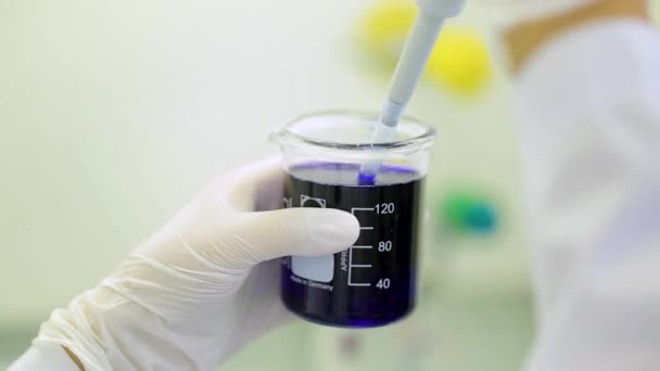 Close-up van glaswerk met blauwe vloeistof in de wetenschapper hand tijdens medische test. Handen van behandelaar stalen tools houden tijdens wetenschappelijk experiment in laboratorium. reageerbuisjes en druppelaar — Stockvideo
