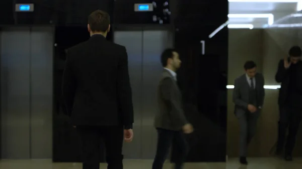 Asansör duran iş takım elbiseli adam, arkadan görüntülemek. Hisse senedi. Asansörde ayakta iş adamı. Asansör yakınındaki koridorda duran iş elbiseli adam — Stok fotoğraf