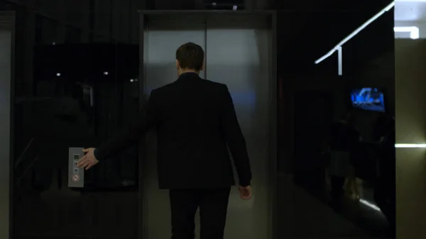 Человек в деловом костюме стоит рядом с лифтом, вид сзади. На складе. бизнесмен стоит у лифта. Человек в деловом костюме стоит в коридоре возле лифта — стоковое фото