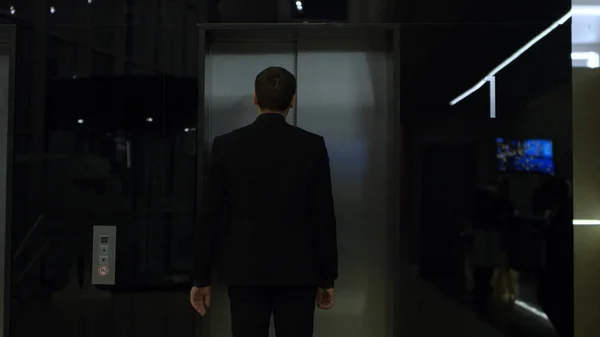Człowiek w garniturze, stojący w pobliżu windy, widok z tyłu. Magazynie. biznesmen znajdował się winda. Człowiek w garniturze stoi na korytarzu blisko windy — Zdjęcie stockowe