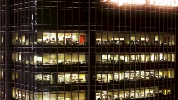 Voo aéreo único ao redor e aproximação para janelas. Iluminação nocturna. Escritórios de fora. Funcionários gerentes trabalham. Edifício de escritório com reflexão de rua em janelas e pessoas — Vídeo de Stock