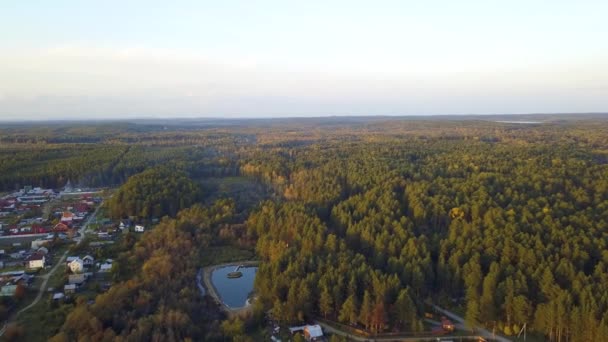 Une petite maison près d'un étang, entourée d'arbres et d'herbe. Vidéo. Vue de dessus de l'étang dans les bois près de la maison 