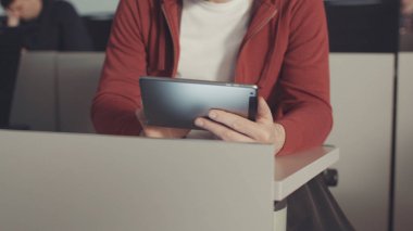 Masa başında oturan genç öğrenci tablet bilgisayar ve okuma kitapları ile etkileşim. Hisse senedi. Eğitim. Üniversitesi