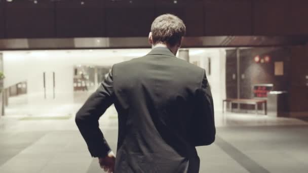 Zadní pohled na mladý podnikatel na sobě tmavý oblek. V UK. Pohled zezadu na podnikatele do hotelu — Stock video