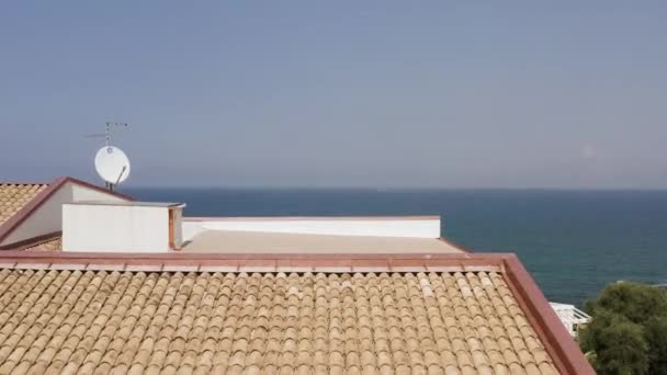 Luchtfoto van de eindeloze blauwe oceaan en lucht boven de verre horizon. Actie. Hoog boven de huizen en het wateroppervlak met twee zeilschepen. — Stockvideo