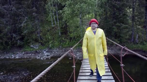 Viaggiatore sul ponte sospeso ammirando viste. Filmati delle scorte. L'uomo in vacanza è venuto a godersi la vista sul ponte di legno e la pipa di fumo — Video Stock