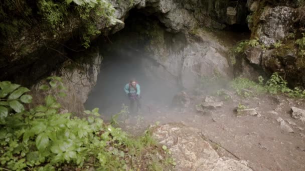 여행자는 동굴에서 올라간다. 주가 영상이요. 탐험가의 로프 취소 보험은 가파른 경사를 따라 바위 속의 어두운 안개 동굴로 올라 갑니다. 극단적 인 야외 활동 — 비디오