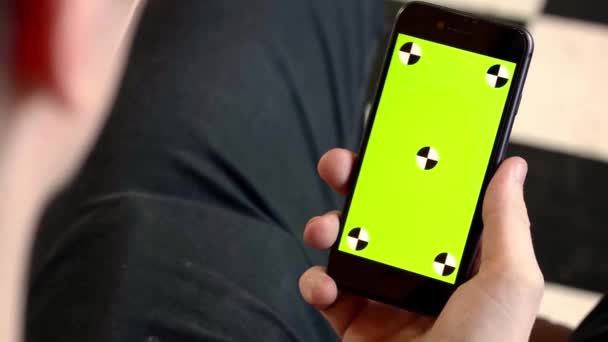 Close-up of man holding phone with green screen. Stock footage. Man holds new smartphone and looks at green screen with dots — 비디오