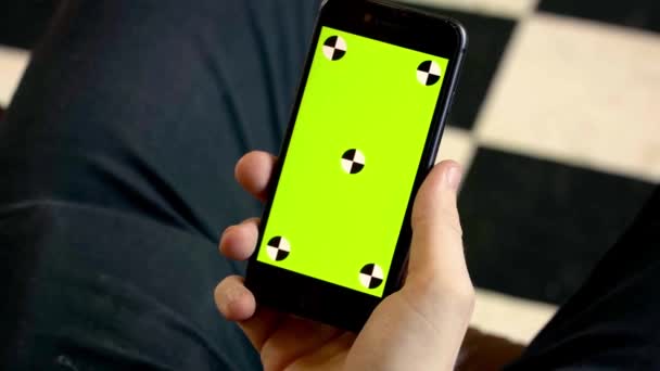 緑の画面で男の携帯電話を保持のクローズアップ。ストック映像だ男は新しいスマートフォンを保持し、ドットと緑の画面を見て — ストック動画