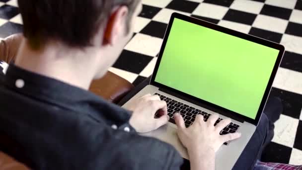 Detailní záběr mladého muže, jak píše do laptopu se zeleným smítkem. Záběry ze skladu. Mladý programátor nebo nezávislý pracovník pracující na notebooku se zelenou obrazovkou — Stock video