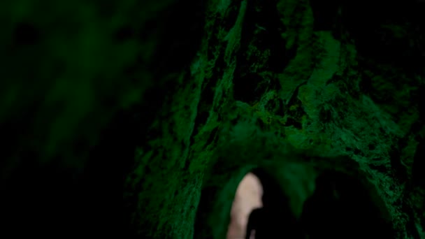 Groep mensen beweegt zich naar de uitgang van de stenen grot met groen licht. Kunst. Mystieke ondergrondse grot onder groen lantaarn licht. — Stockvideo