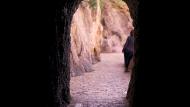 Saia da caverna de pedra escura com uma mulher do lado de fora. Arte. caverna subterrânea mística dentro da montanha sob a luz do sol . — Vídeo de Stock