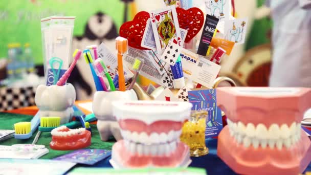 Gros plan de la table dans le bureau de la dentisterie pour enfants avec mâchoire, brosses à dents et dentifrice sur fond mural vert. L'art. Développement du concept d'hygiène . — Video