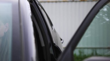 Caddedeki kadın açık araba kapısını kapatın. - Sanat. Gri metal arka planda bir kadın tarafından açılan koyu renk araba kapısı..