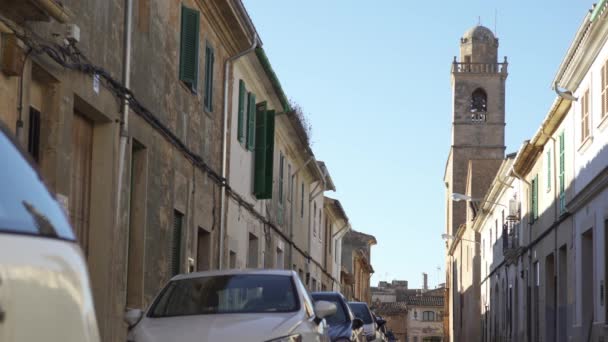 Rue étroite et calme de la ville avec des voitures garées le long des vieilles maisons sur fond bleu ciel nuageux. L'art. Quelqu'un ouvre les volets verts . — Video