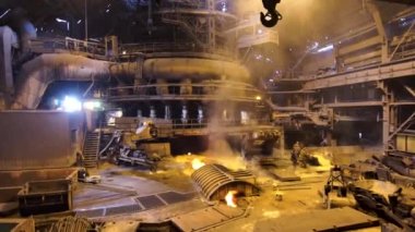 Sıcak atölyedeki fabrika işçilerine yaklaşan kamera, ağır endüstri konsepti. Stock Video. Metalürji endüstrisi, çelik üretim süreci.