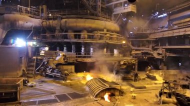 Sıcak atölyedeki fabrika işçilerine geri hareket eden kamera, ağır endüstri konsepti. Stock Video. Metalürji endüstrisi, çelik üretim süreci.