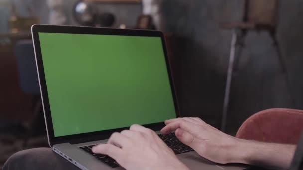 Über die Schulteransicht eines Mannes, der an seinem Schreibtisch sitzt und an einem Laptop mit grünem Bildschirm arbeitet. Archivmaterial. Mann benutzt Notebook mit Chroma-Schlüssel. — Stockvideo