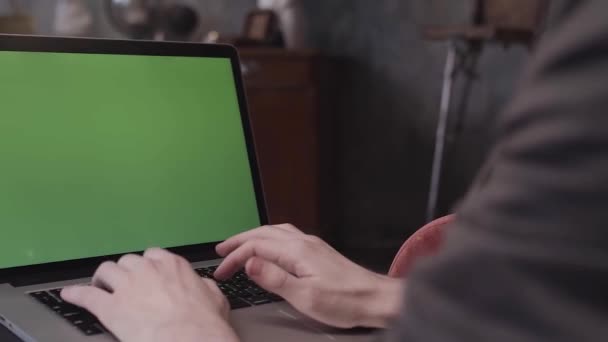 Vista trasera de cerca de las manos de un joven hombre de negocios escribiendo en un teclado portátil con una pantalla verde editable en blanco. Imágenes de archivo. Hombre usando el ordenador portátil con croma key . — Vídeos de Stock