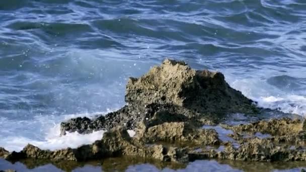 Malé vlny dopadají a šplouchají na mořský břeh. Akce. Vlny narážejí do skály. Šplouchání mořských vln na malých skalách — Stock video