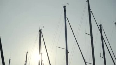Güneş ve mavi gökyüzünün arka planındaki gemi direklerinin güzel manzarası. Başla. Yatların direkleri, deniz yolculuğuna çağıran sıcak güneş ışığıyla aydınlanır.