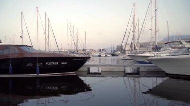 Güzel yatlar iskelede duruyor güzel gökyüzünde suya yansıyan. Başla. Güney deniz şehrinin iskelesinde direkleri olan güzel pahalı yatlar.