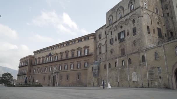 Gammal historisk byggnad med fästning vägg med vandrande turister på bakgrunden av himlen. Börja. Grå hög gammal byggnad i Europas historiska stad — Stockvideo