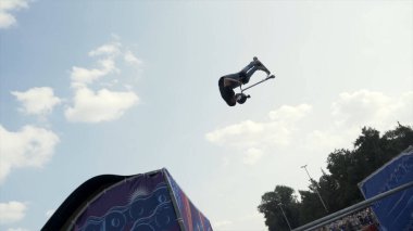 İngiltere - Londra 04.28.2019: Scooter Park yarışmasında profesyonel bir binici, spor ve aktif yaşam tarzı konsepti. Başla. Sıçrama tahtasından atlayan motosikletli..