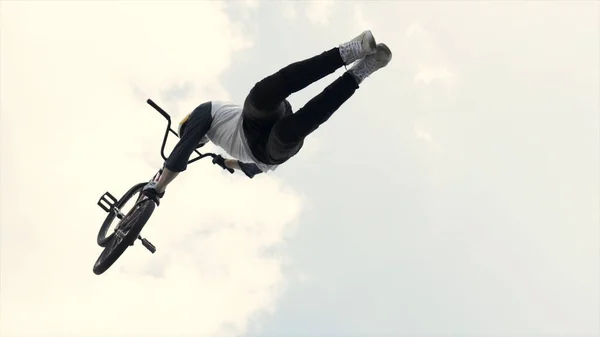 Rússia - Moscou, 08.15.2019: dois pilotos em competição saltando de um trampolim no fundo azul do céu nublado. Acção. Dois pilotos BMX fazendo truques . — Fotografia de Stock