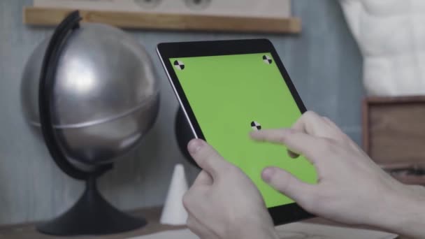 Les mains d'un jeune inconnu tapotant et défilant sur un ordinateur portable avec écran vert sur une table en bois à côté d'un globe d'argent. Images d'archives. Homme utilisant son Ipad avec clé chromatique . — Video