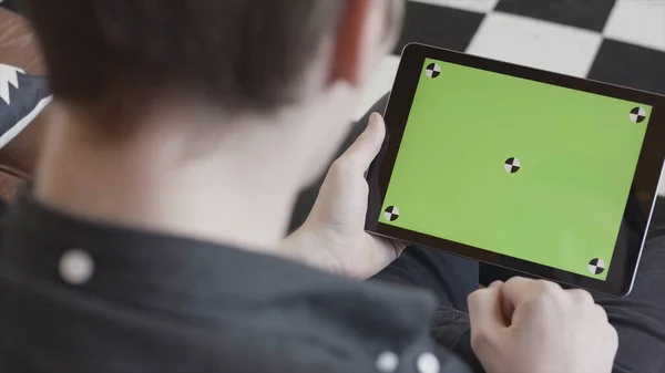 Technology and internet concept, over the shoulder view of a man tapping on the green screen of a tablet with tracking marks. Stock footage. Close-up of man in black shirt using his device with chroma — Stock Photo, Image