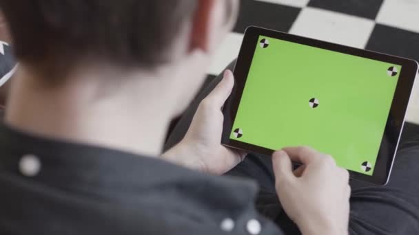 Technologie en internet concept, over de schouder van een man tikken op het groene scherm van een tablet met tracking marks. Voorraadbeelden. Close-up van de mens in zwart shirt met behulp van zijn apparaat met chroma — Stockvideo