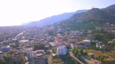 Yaz şehrinin havadan görünüşü, bir sürü bina ve yeşil ağaçlar. - Sanat. Mavi bulutlu arka planda deniz kıyısına yakın büyük bir güney şehri. .