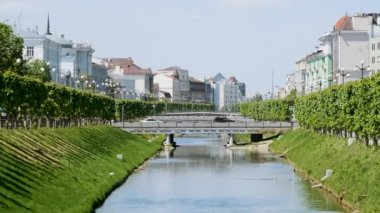 Nehir boyunca yeşil ağaçları ve beyaz evleri olan güzel bir şehir manzarası. Stok görüntüleri. Eski Orta Avrupa kentindeki nehir kanalı boyunca romantik evler.