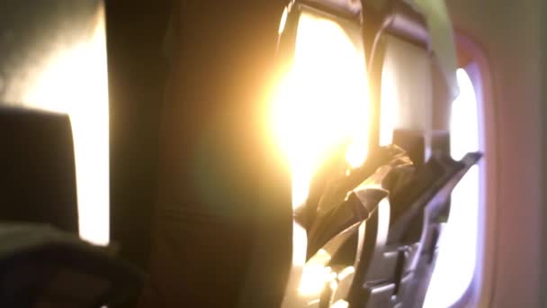 La luz del sol al amanecer brillando a través de la ventana del avión y el asiento, concepto de viaje. Filmación. Vista interior de un avión . — Vídeo de stock