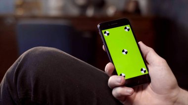 Evde cep telefonu kullanan bir adam. Stok görüntüleri. Bir adamın elinde yeşil ekran olan bir telefonu kapat.