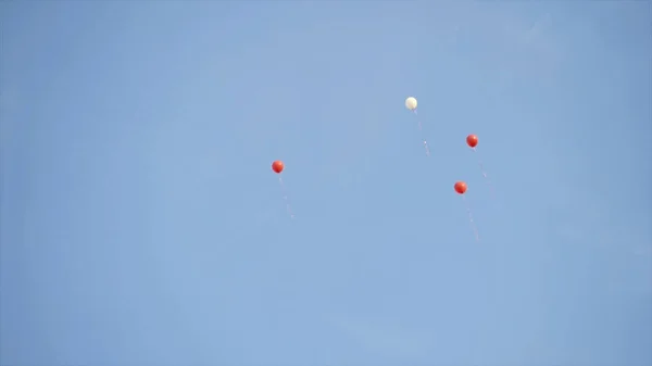 Ballonger flyger högt på himlen. Börja. Röda ballonger flyger in i blå höjder av klar himmel. Festliga dekorationer i form av ballonger flyger upp i skyn — Stockfoto