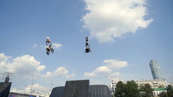 Motociclista realiza acrobacias com salto no festival de Moto. Acção. Desempenho com moto e snowmobile no trampolim do festival Moto — Fotografia de Stock