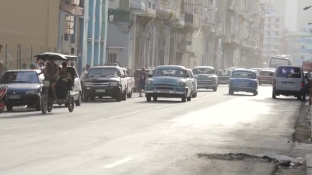 Havanna, Kuuba - toukokuu, 2019: Kuubalaiset läpäisevät värikkään amerikkalaisen auton. Toimintaa. Elämä Havannan kaduilla kulkee vintage-autoja — kuvapankkivideo