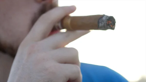 Gros plan d'un homme à lunettes qui fume un cigare. L'action. Blanc bel homme barbu dans des lunettes élégantes cigare fumant dans la rue — Photo