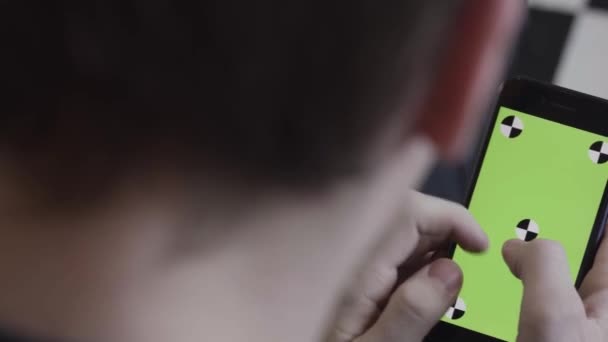 Man handen met behulp van mobiele smartphone met groen scherm, over de schouder te bekijken. Voorraadbeelden. Close-up van man scrollen en tikken op Iphone scherm met chroma sleutel. — Stockvideo