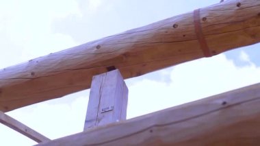 İnşaat halindeki ahşap bir binanın alt tarafında. Şarjör. Ahşap çerçeve, bulutlu arka planda ahşap kirişler, marangozluk işleri..