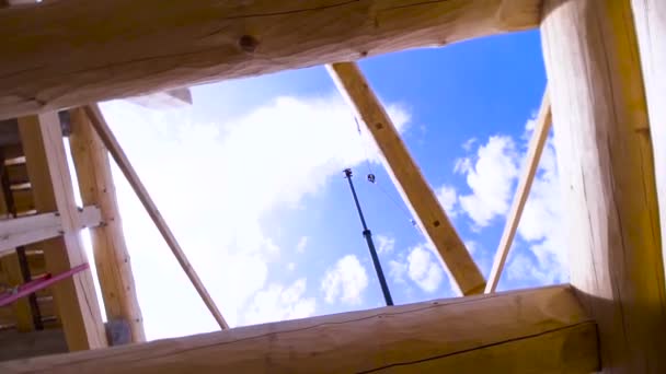 Blick von unten auf ein neues Wohnhaus vor blauem Himmel und Wolken. Clip. Unfertiges ökologisches Haus aus Holzbalken. — Stockvideo