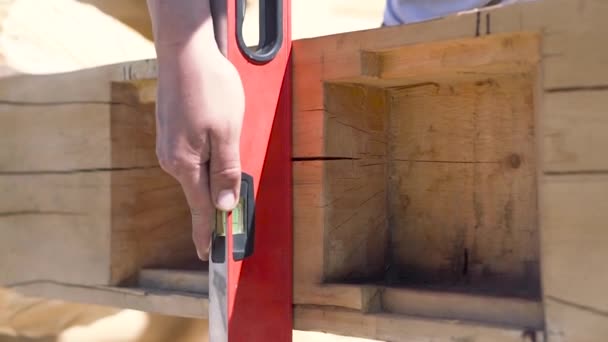 Nahaufnahme eines Tischlers, der eine Konstruktionsebene am Holzbalken montiert. Clip. Prozess des Holzhausbaus, professionelle Ausstattung. — Stockvideo